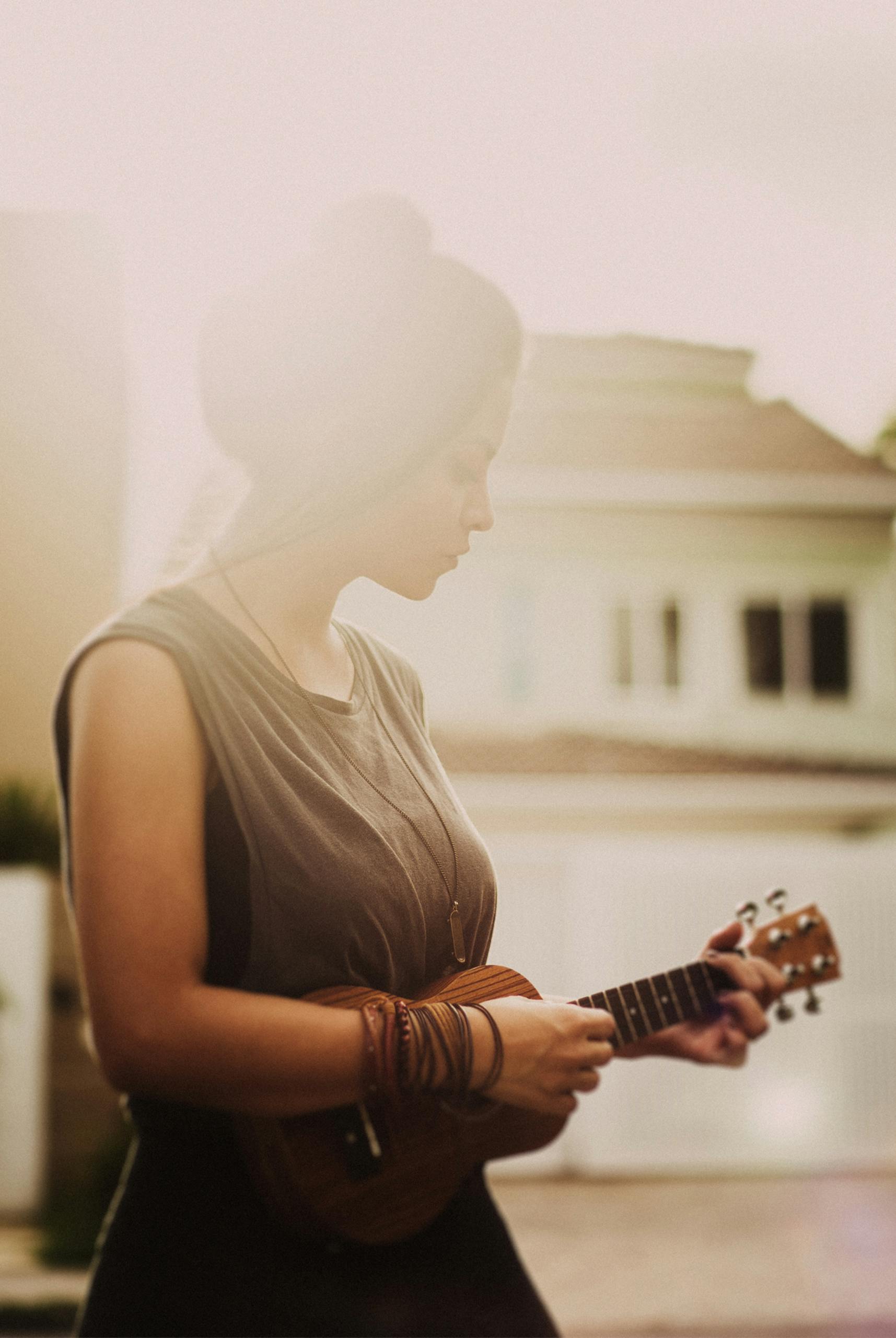 Woman in Brown Sleeveless Dress While Playing Ukulele